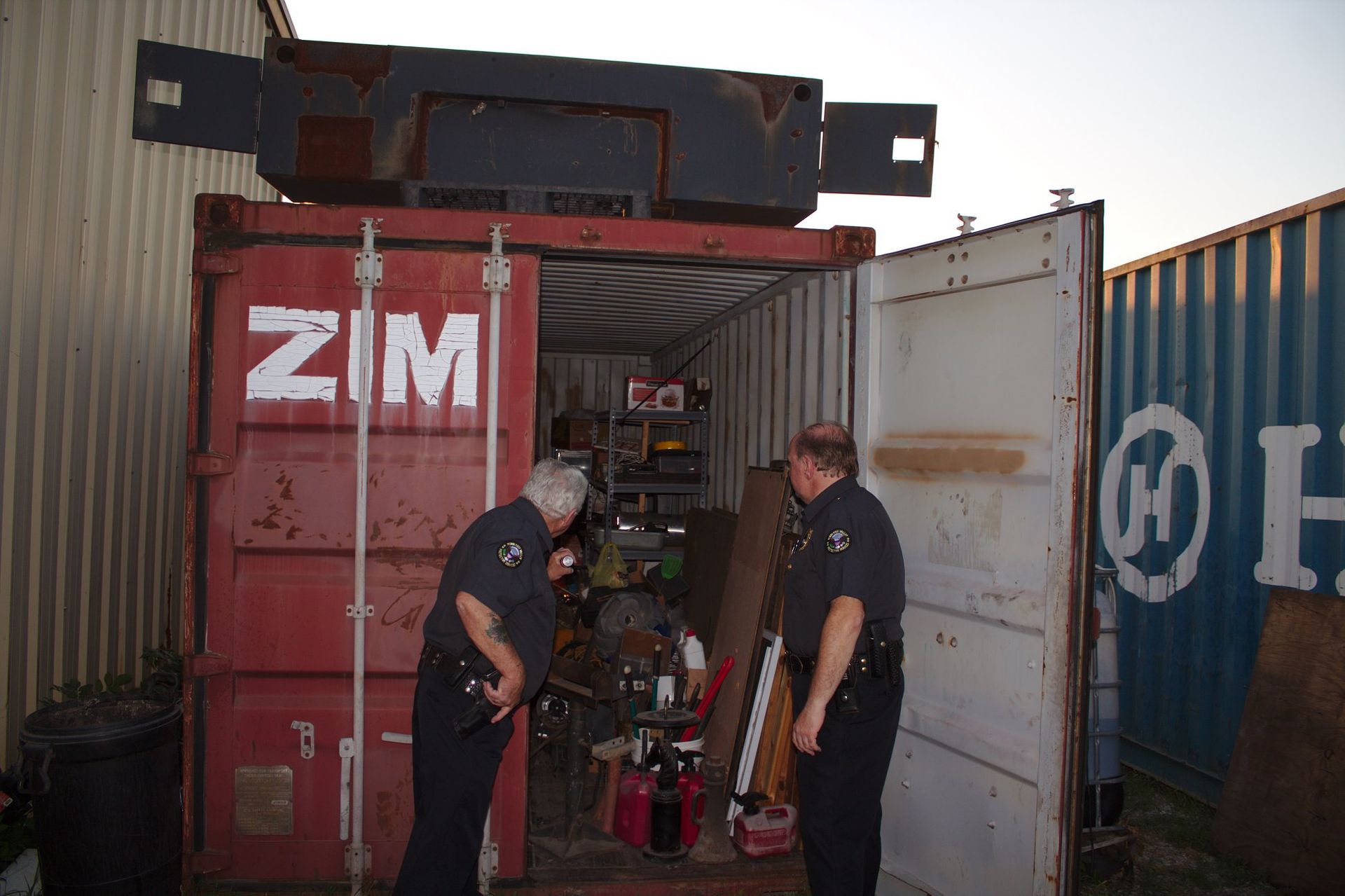 two security officers are inspecting a red shipping container