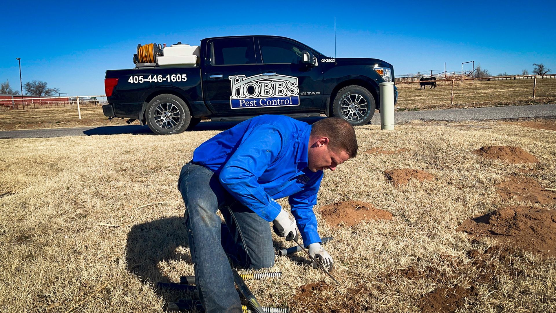 Man kneeling, digging in dirt, truck labeled 