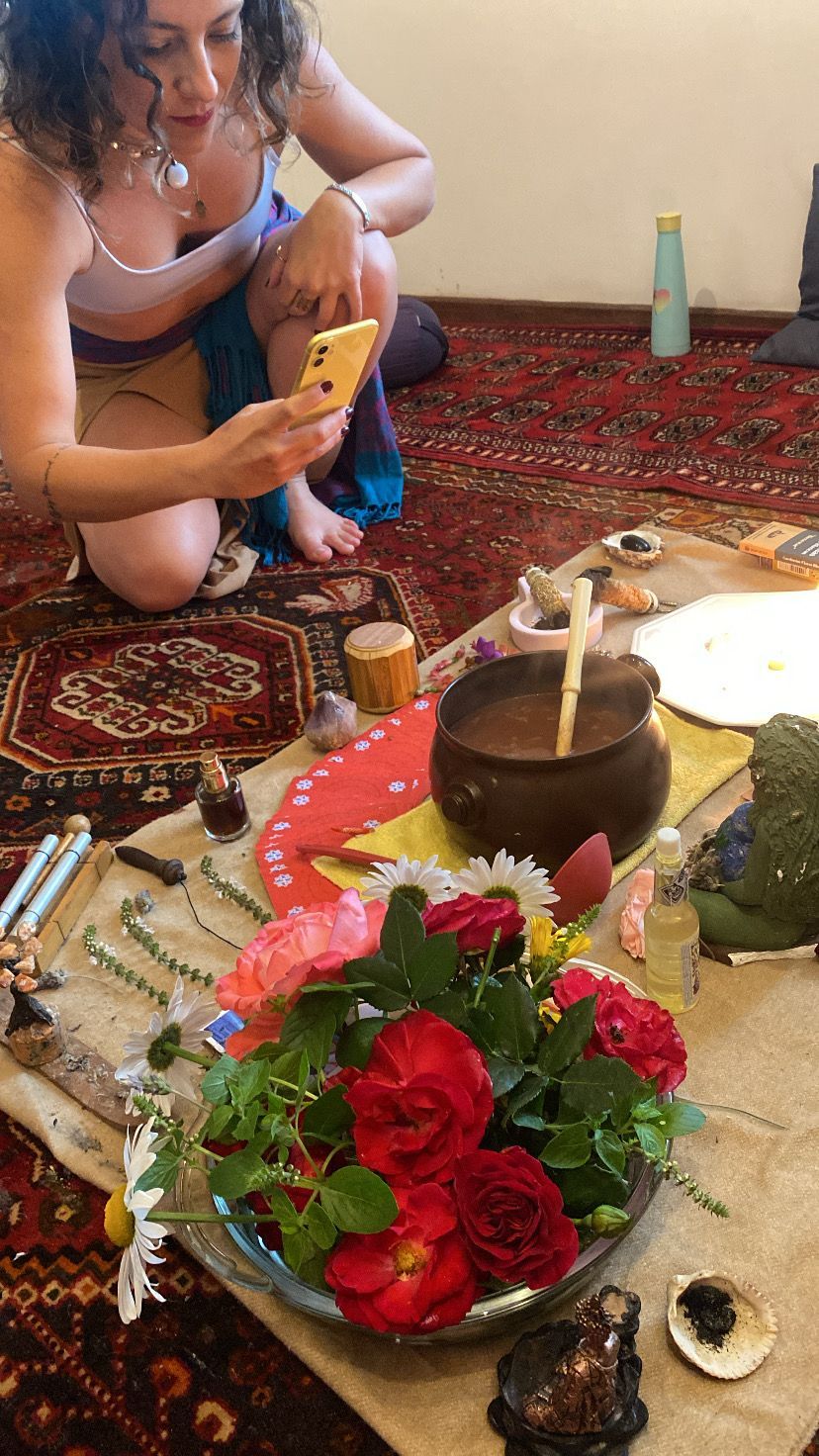 Mulher tirando foto de flores e itens rituais em um tapete.