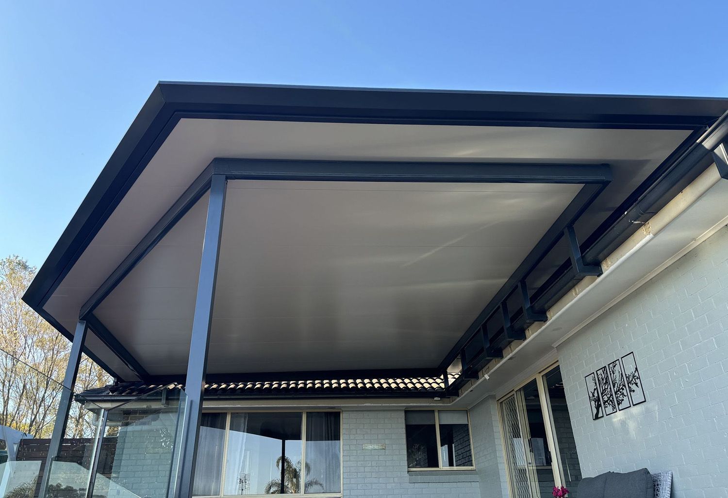 A Covered Patio With A Gray Roof And Black Beams