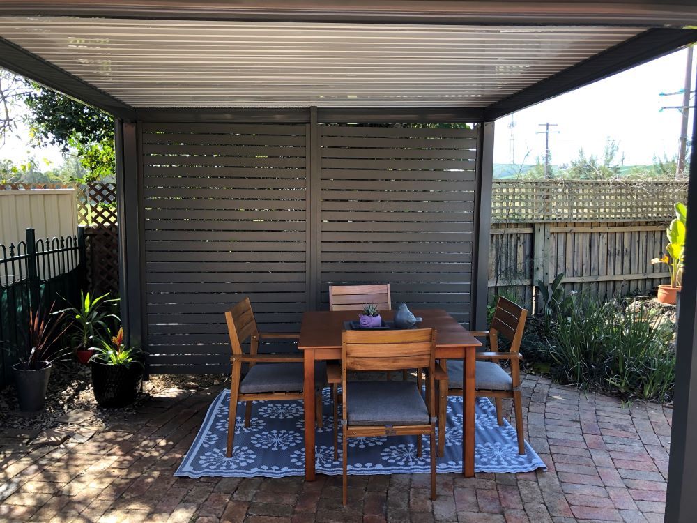 A Patio With a Table and Chairs Under a Pergola — Outdoor Leisure Living In Tuggerah, NSW