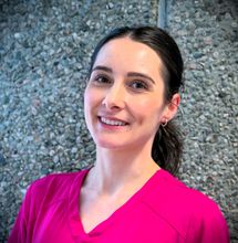 Tannlege Christian med briller og skjegg, iført blå skjorte og medisinsk maske, smiler til kameraet.