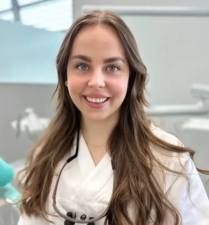 Tannlege Christian med briller og skjegg, iført blå skjorte og medisinsk maske, smiler til kameraet.