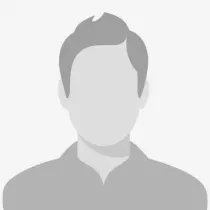 Tannlege Christian med briller og skjegg, iført blå skjorte og medisinsk maske, smiler til kameraet.