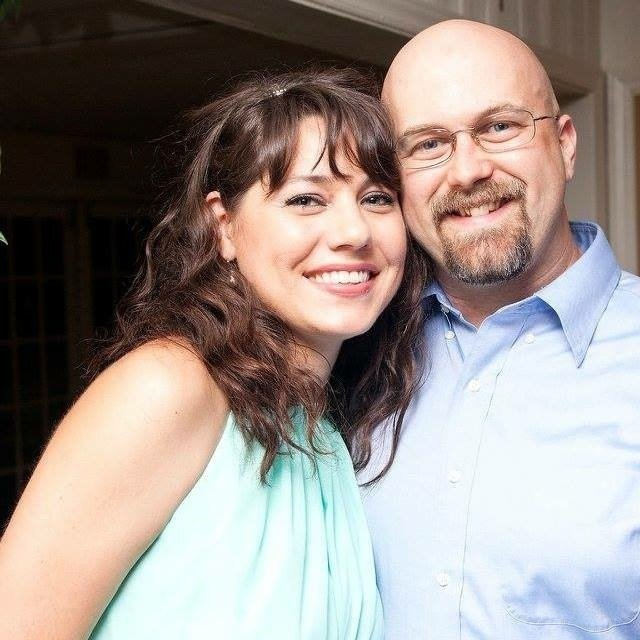A man and a woman are posing for a picture and smiling for the camera