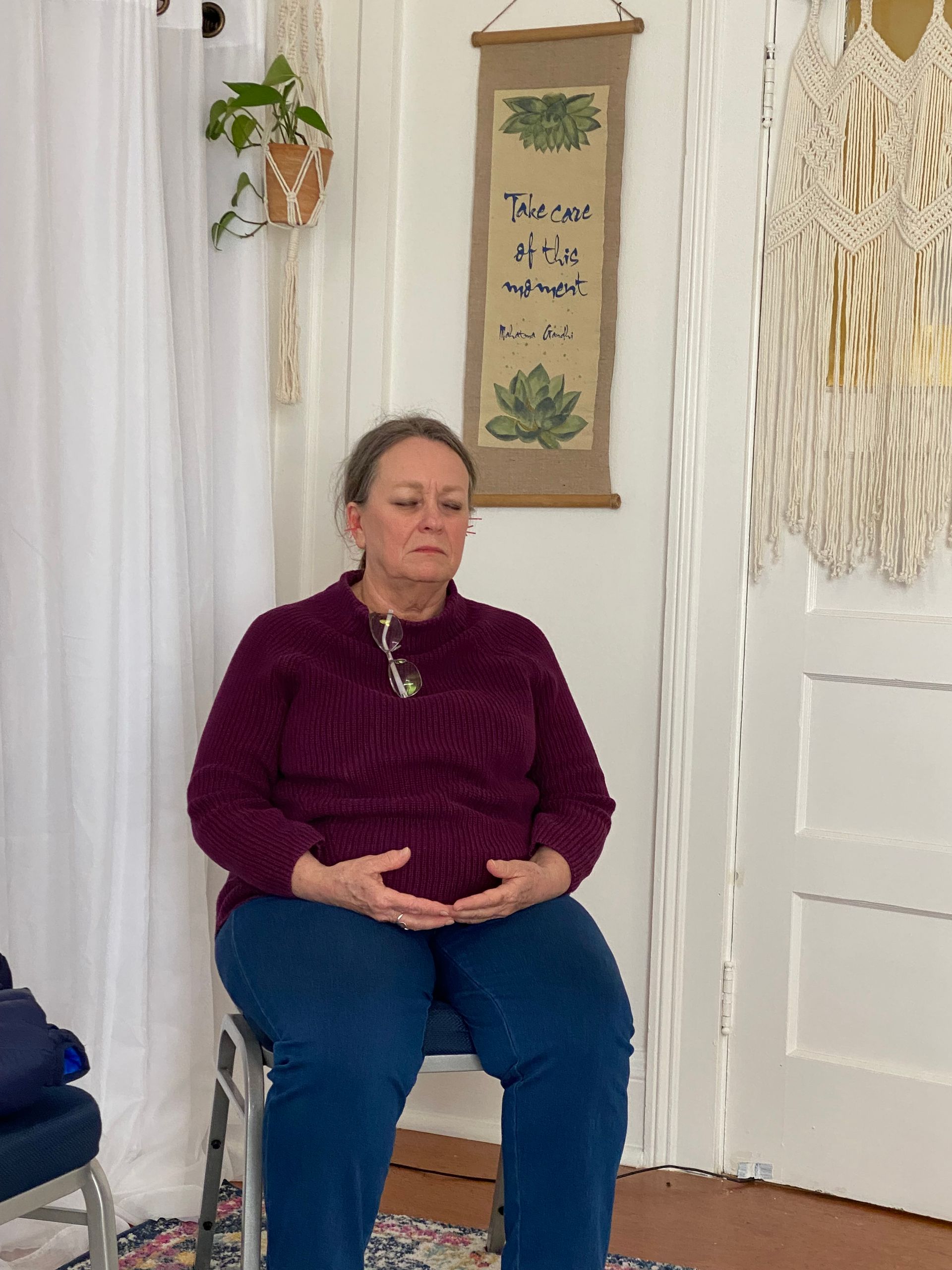 A woman in a purple sweater is sitting on a chair in a room.