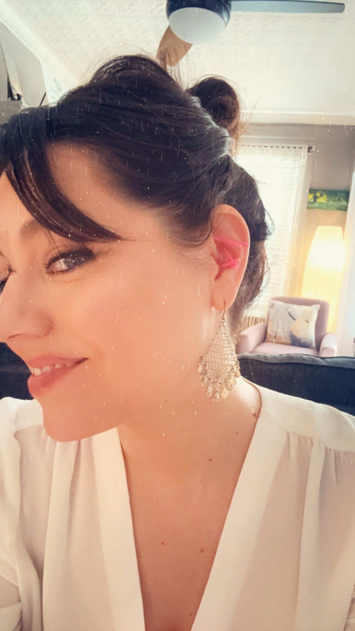 A close up of a woman wearing earrings and a white shirt.