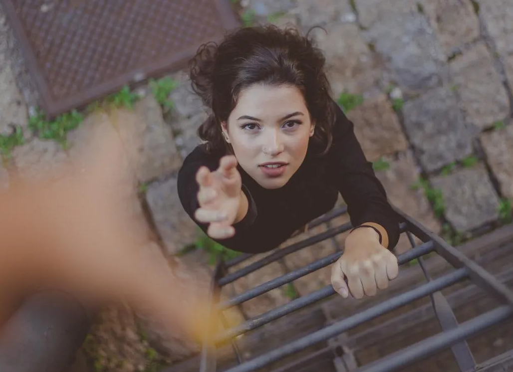 A woman is climbing up a set of metal stairs.