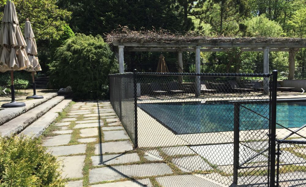 A chain link fence surrounds a large swimming pool.