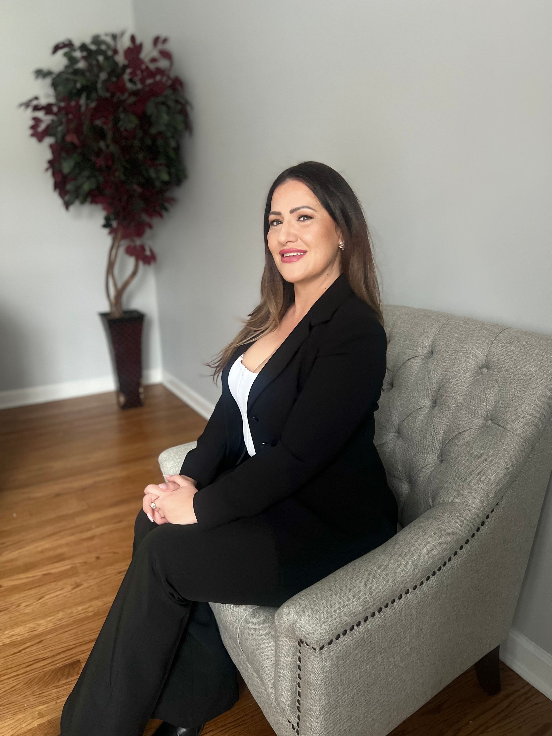 A woman is sitting at a desk with a laptop and a vase of flowers.