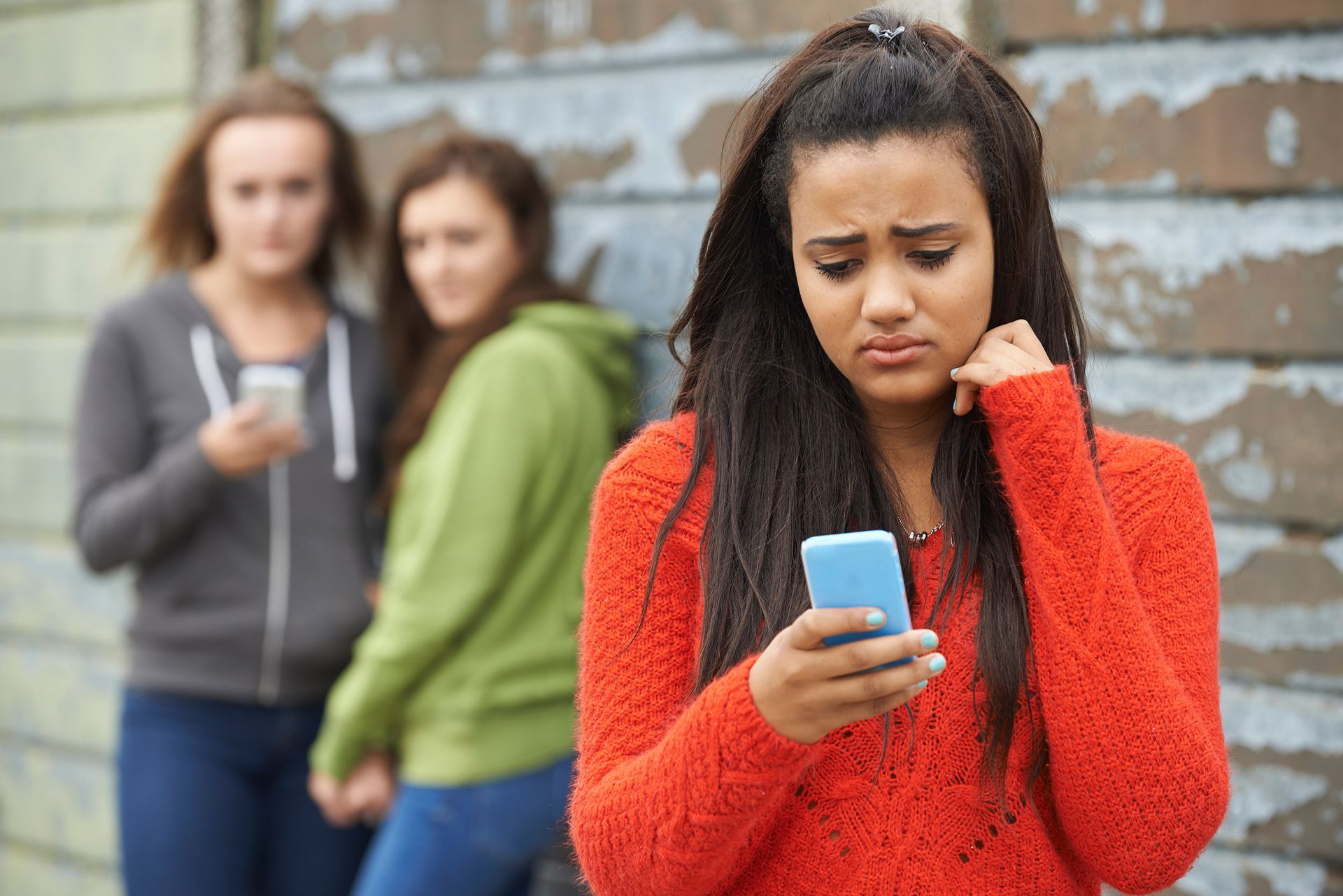 a girl in an orange sweater is looking at her phone