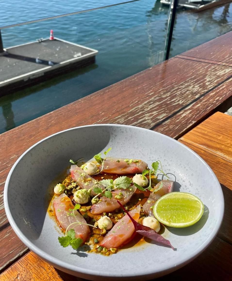 A Bowl Of Food Is Sitting On A Wooden Table Next To A Body Of Water — Northern Rivers Seafood In Ballina, NSW