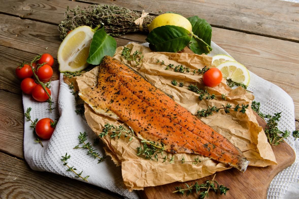 A Piece Of Smoked Salmon Is Sitting On A Piece Of Paper On A Wooden Table — Northern Rivers Seafood In Ballina, NSW