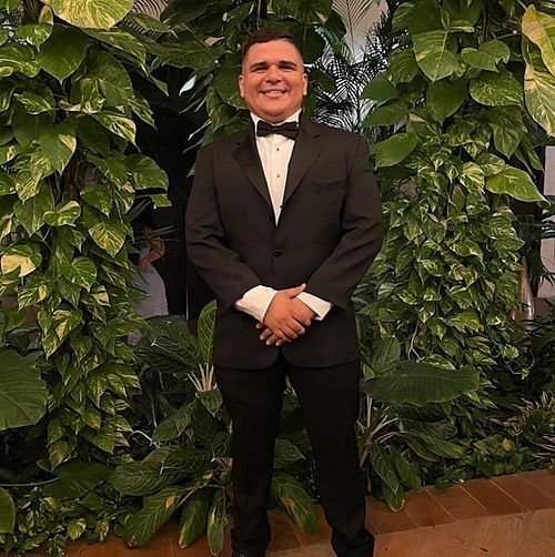 Persona sonriente con traje y corbata, sobre un fondo claro. | Mevak Agency