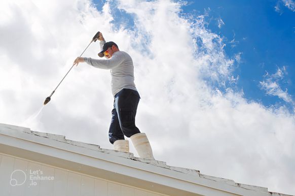 A man is cleaning the roof of a house with a soft pressure washer for Home Restore in Sunderland, UK.