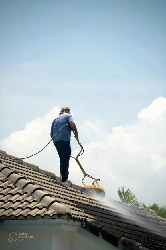 A man is cleaning the roof of a house with a soft pressure washer for Home Restore in Sunderland, UK.