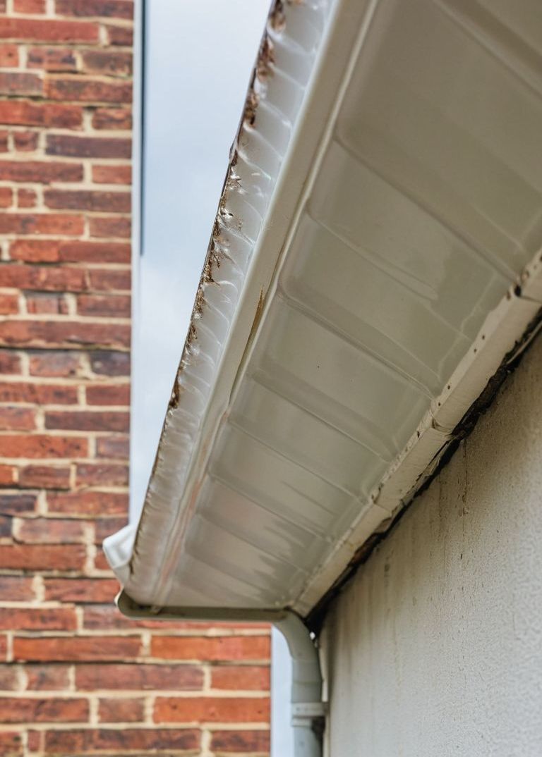 A white gutter is on the side of a brick building.