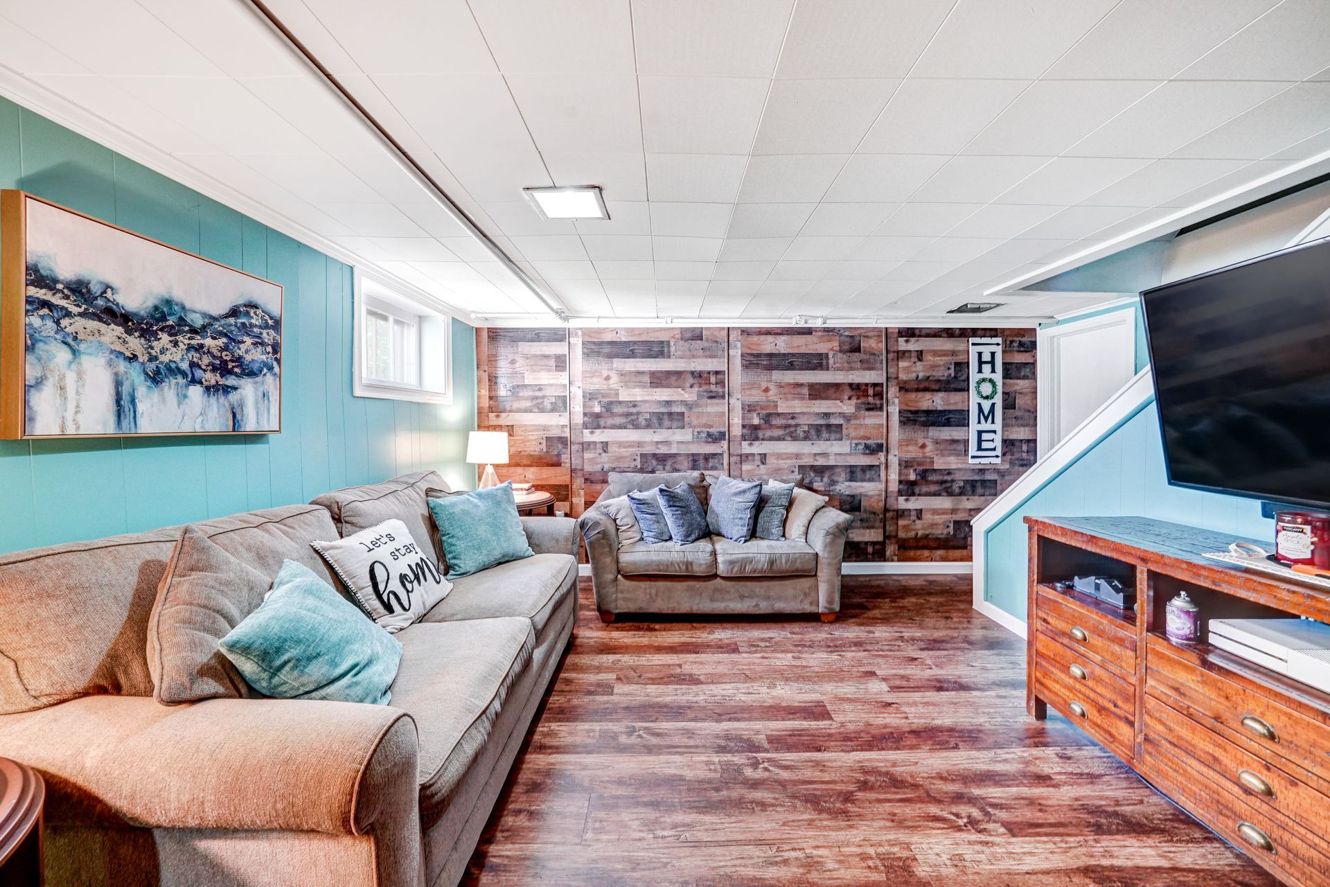 Cozy living room with turquoise and wood walls, two couches, and a TV on a wooden console.
