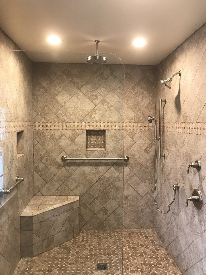 Tiled walk-in shower with a seat and grab bars, neutral colors, and glass door.