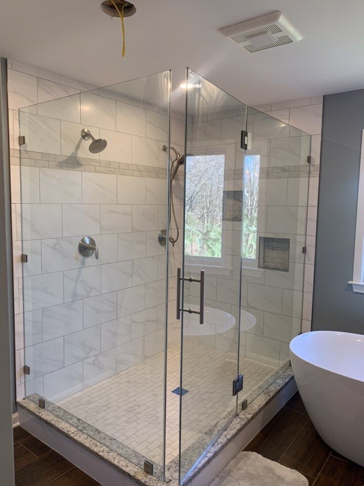 Glass shower enclosure with white tile walls and floor, and chrome fixtures.