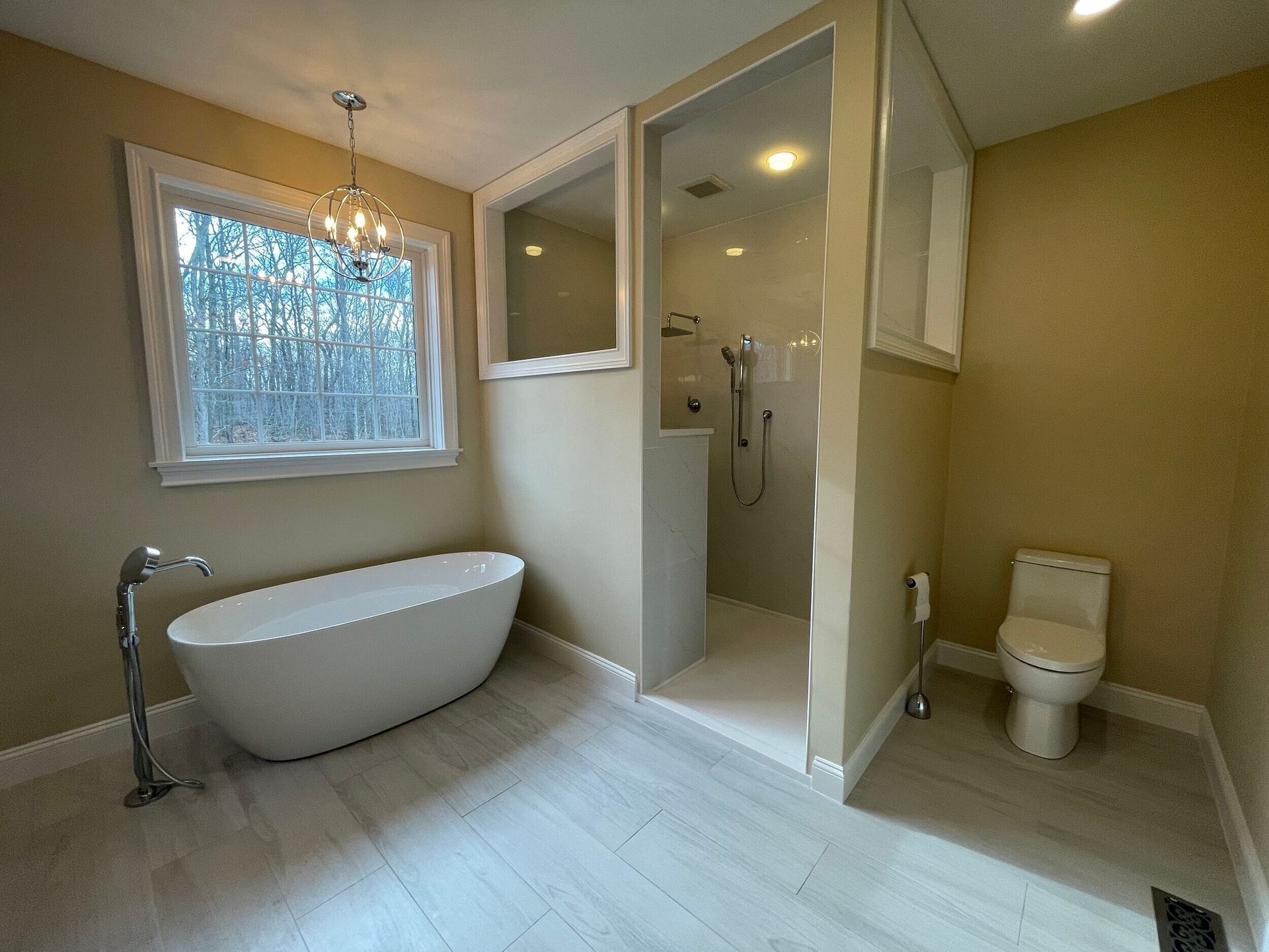 Modern bathroom with a freestanding tub, glass shower, and toilet.