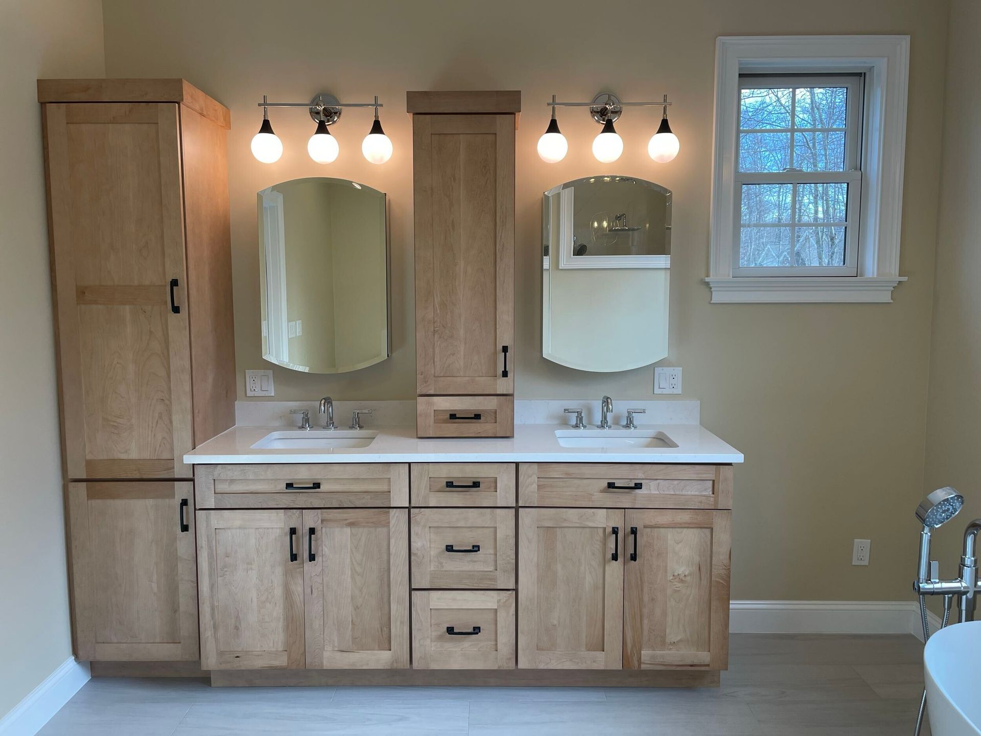 Bathroom with two vanities, two mirrors, and two tall storage cabinets in light wood.