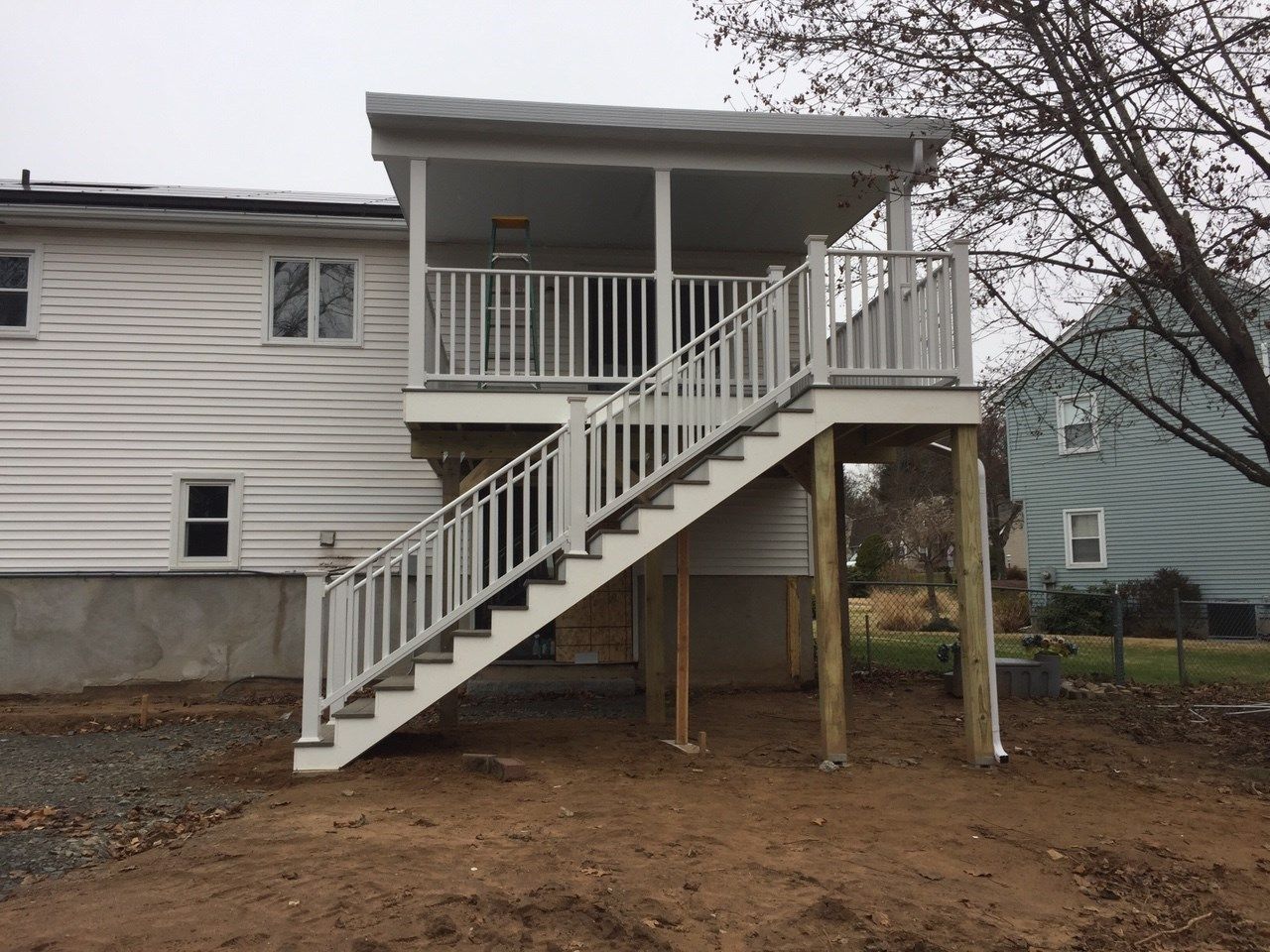 White deck and stairs with a covered roof attached to a white house.