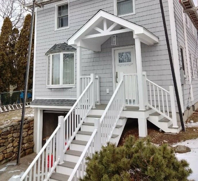 Gray house with white stairs, entry porch, bay window, and a door.