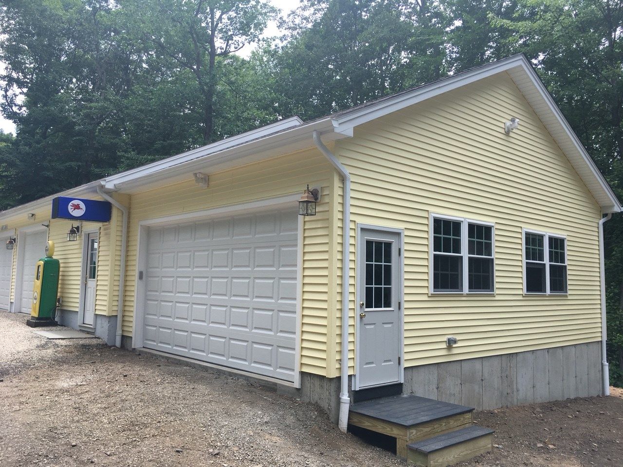 Yellow garage with white garage doors, entry door, windows, and small steps.