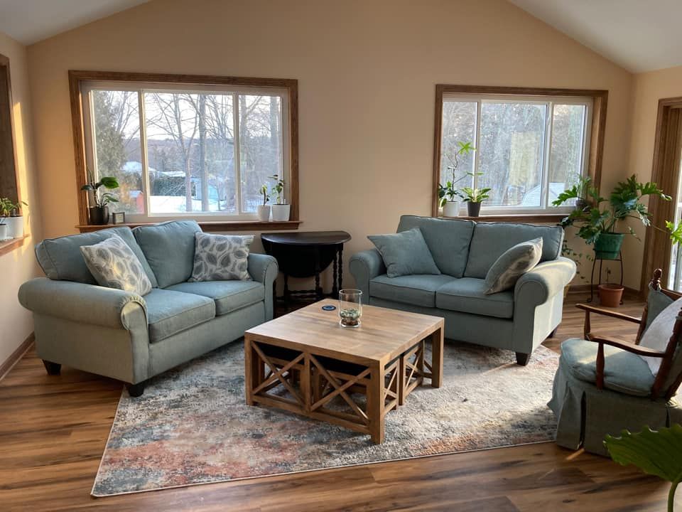 Living room with two blue sofas, wooden coffee table, rug, and windows.