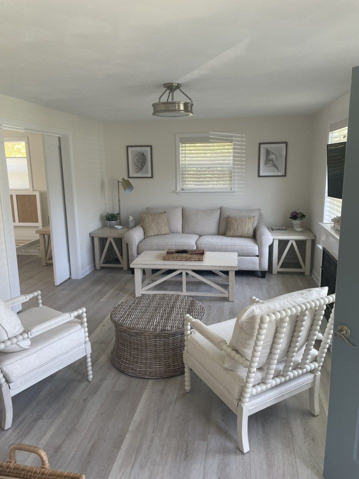 Living room with light wood floors, white walls, and neutral-toned furniture.