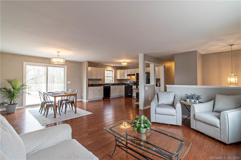 Open-concept living space with dining area, kitchen, and living room; hardwood floors, neutral colors.