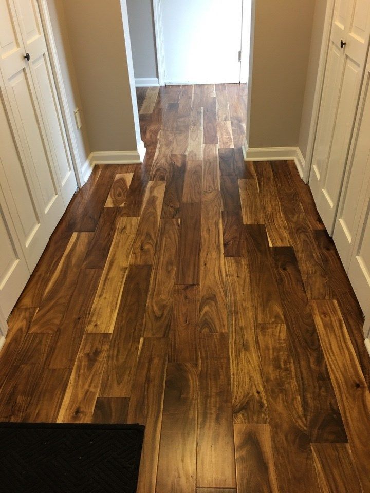 Hallway with hardwood floor, flanked by white cabinets, leading to a door.
