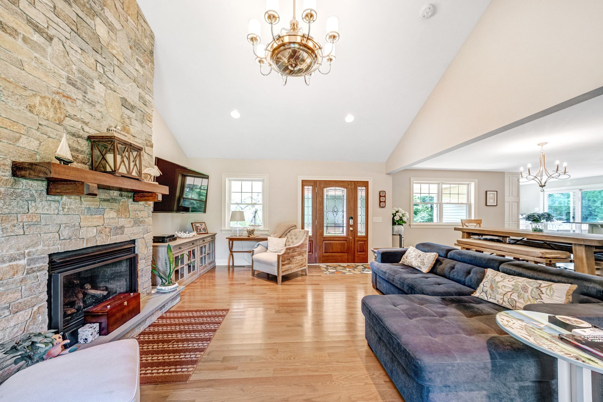 Spacious living room with stone fireplace, wood floors, and blue sofa.