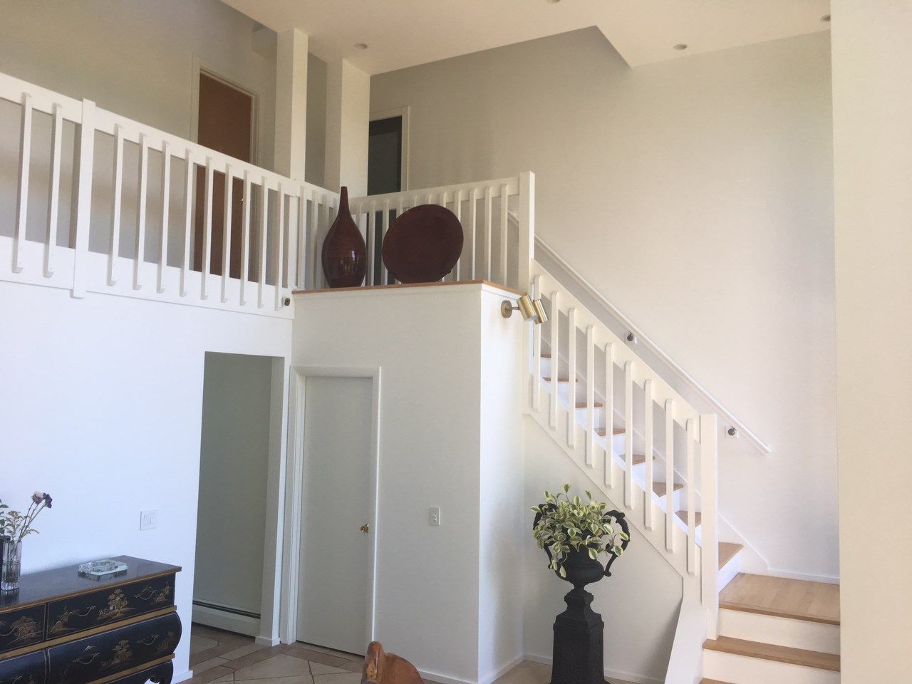 Interior view of a white staircase and loft area with decorative vases.