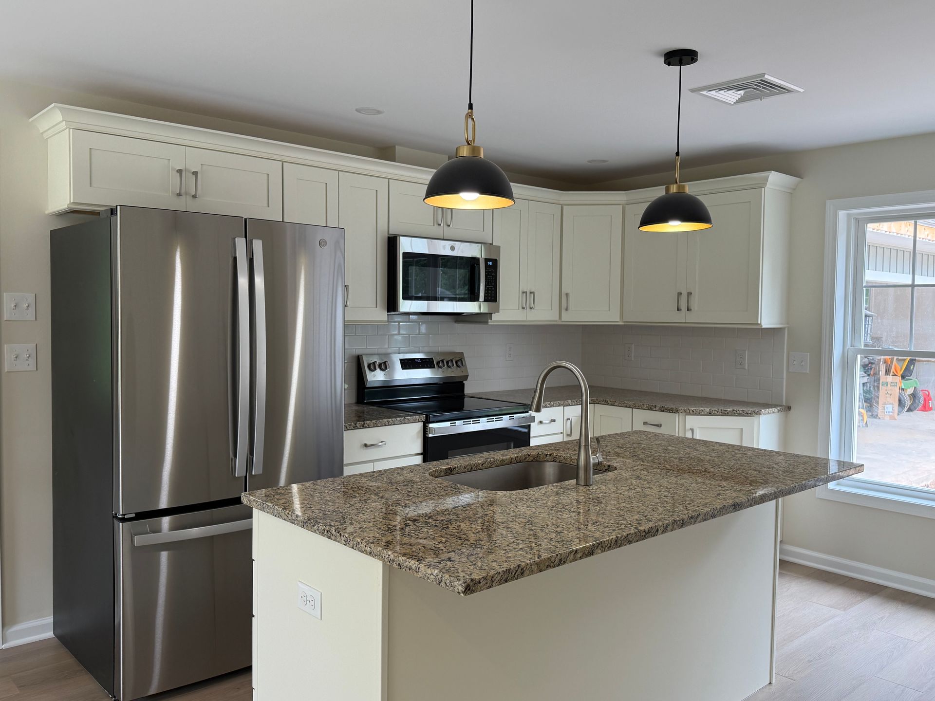 Modern kitchen with stainless steel appliances, granite countertops, and light fixtures.