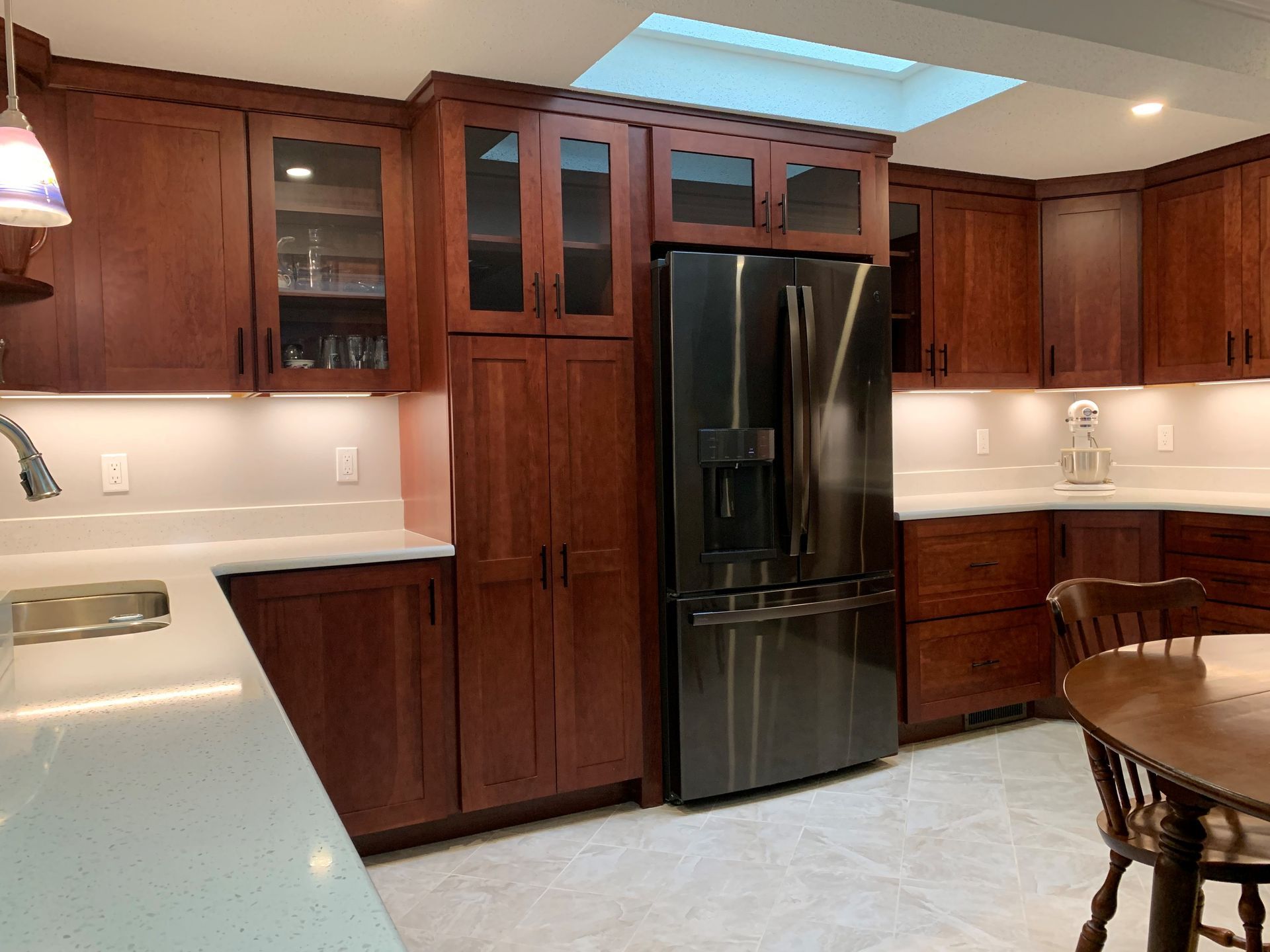 Kitchen with dark wood cabinets, stainless steel refrigerator, and skylight.