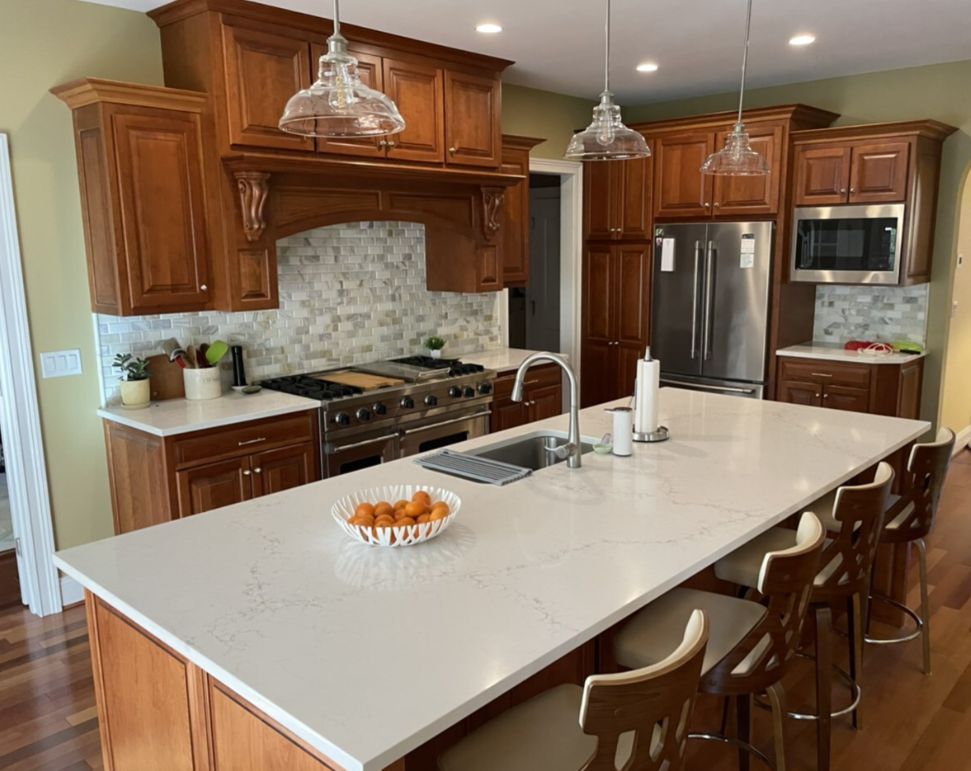 Kitchen with wooden cabinets, white countertops, stainless steel appliances, and a central island with seating.
