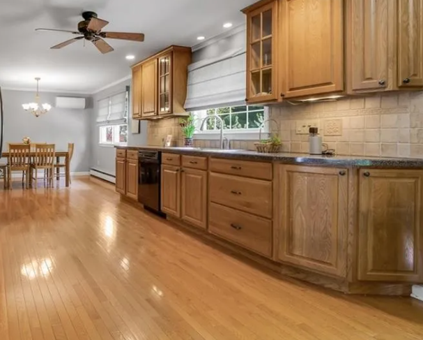 Wooden kitchen cabinets with hardwood floors and a dining area.