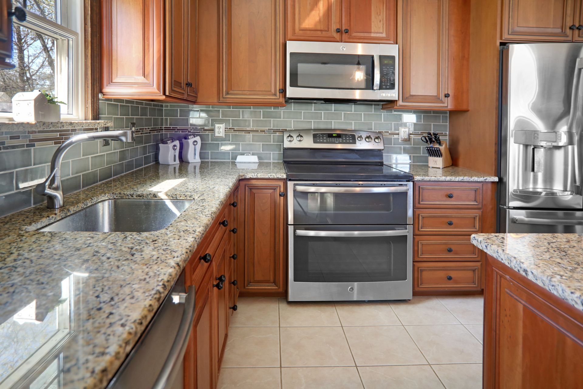 Kitchen with light-colored countertops, brown cabinets, stainless steel appliances, and a tiled backsplash.