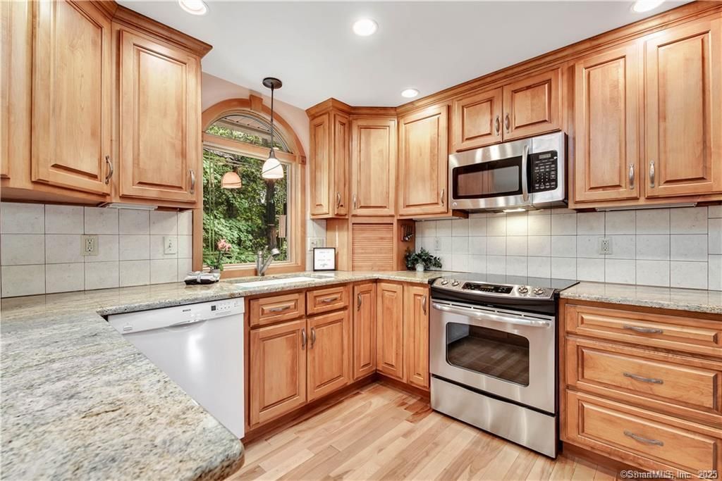 Kitchen with wooden cabinets, stainless steel appliances, and granite countertops.