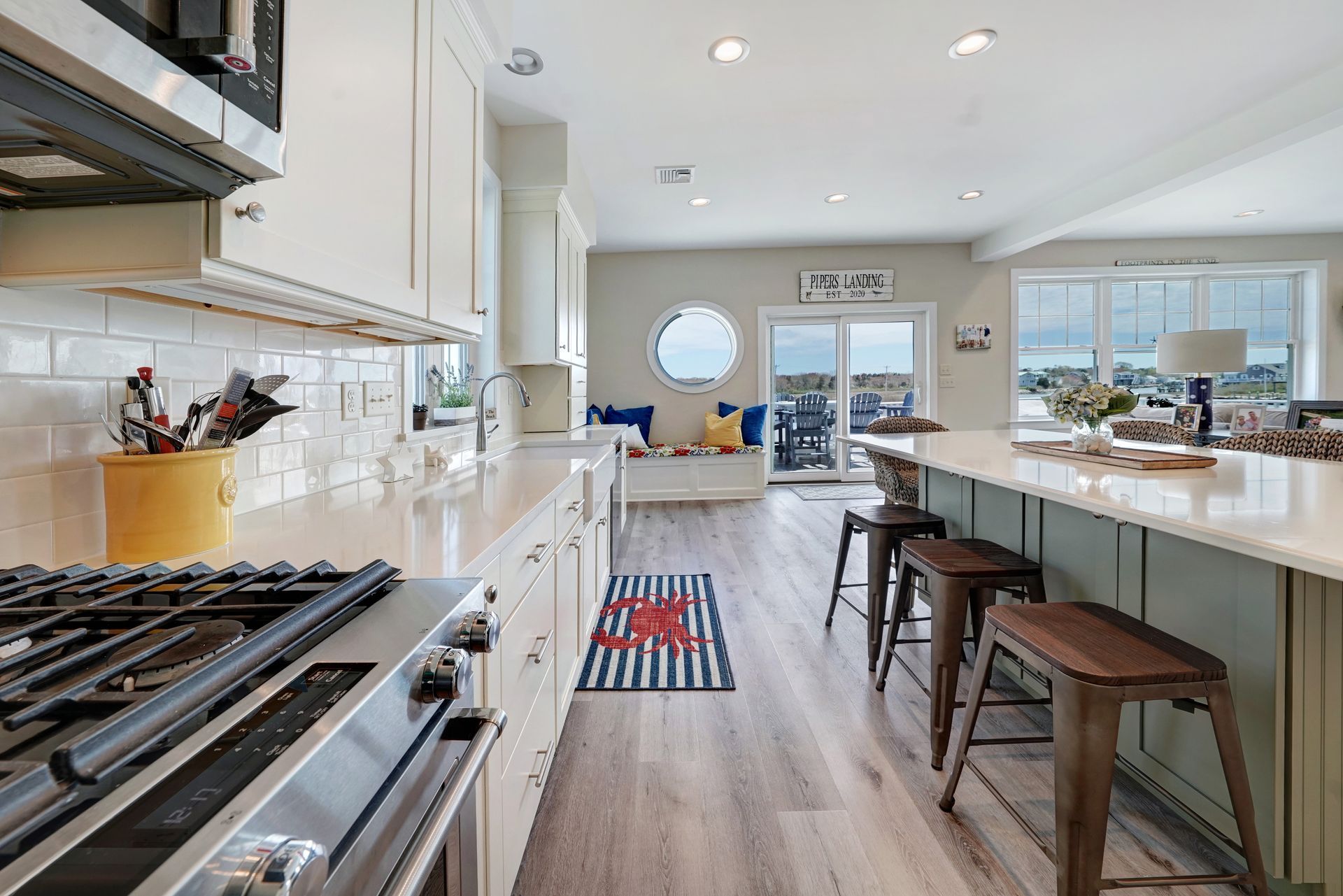 Modern kitchen with white cabinets, stainless steel appliances, and a green island with bar stools.