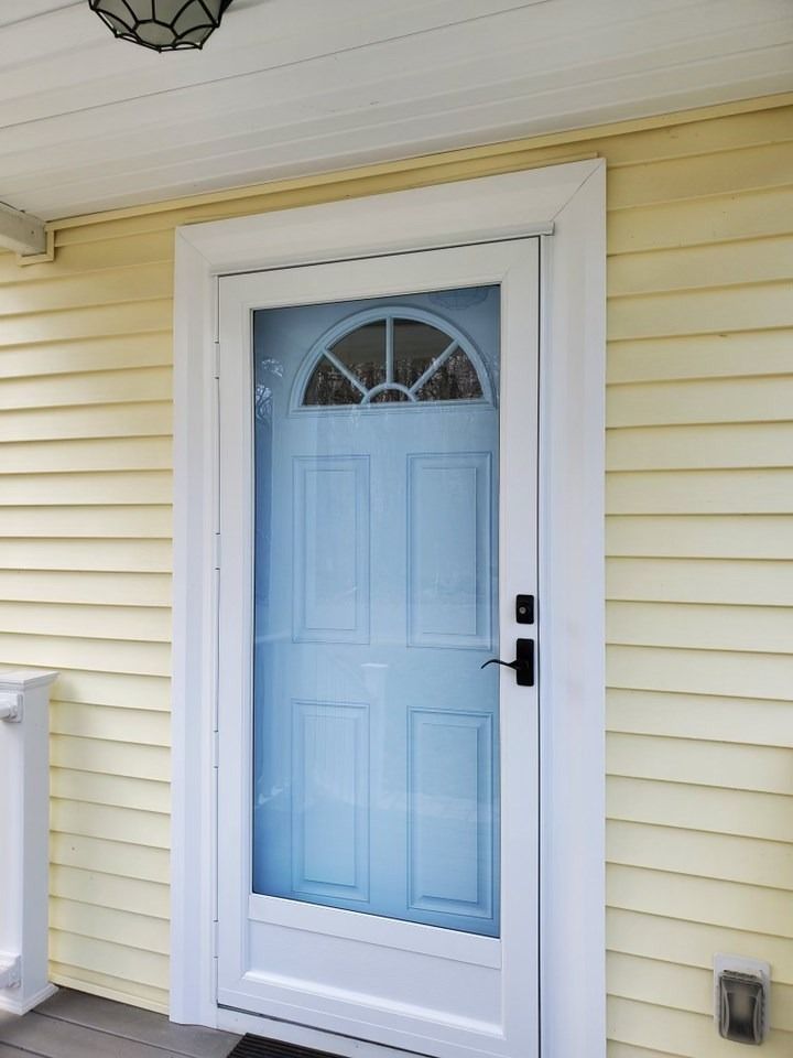 Blue front door with screen, white trim, on a yellow house.