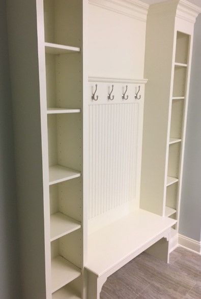 Built-in white mudroom cabinet with shelving, hooks, and bench.