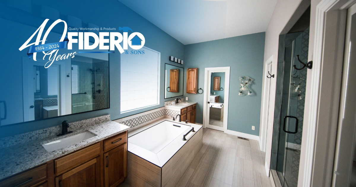 A modern, spacious bathroom with blue walls, a white tub, light wood vanity cabinets, and light wood-look flooring.