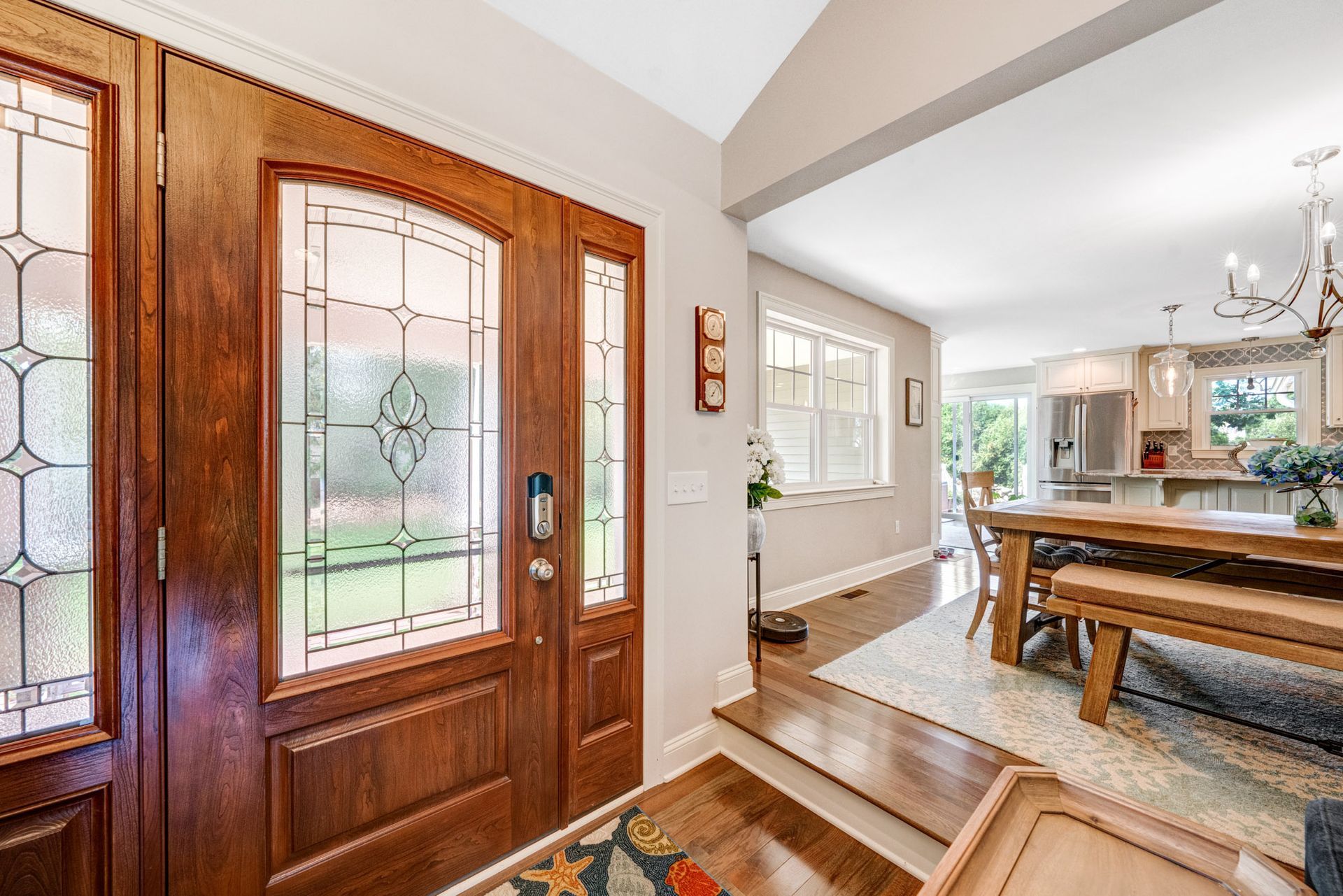 Wooden front door with glass panels; entry hall opens to dining area.