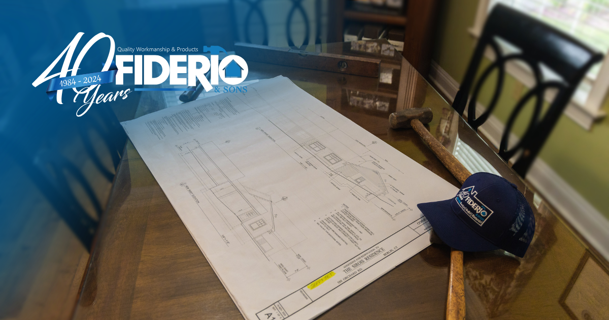 Blueprints, a hammer, and a baseball cap on a glass table with a 