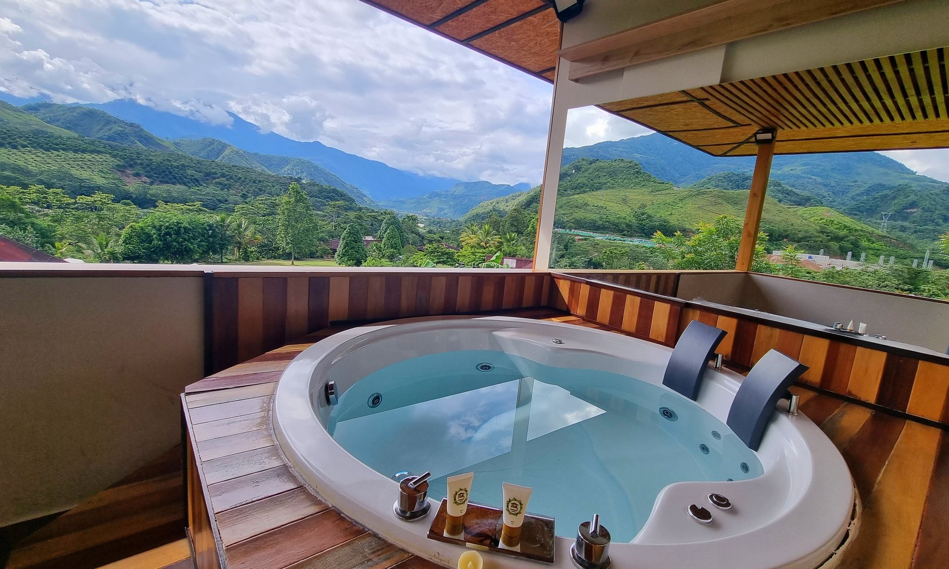 Bañera de hidromasaje en terraza de madera con vistas a la montaña.