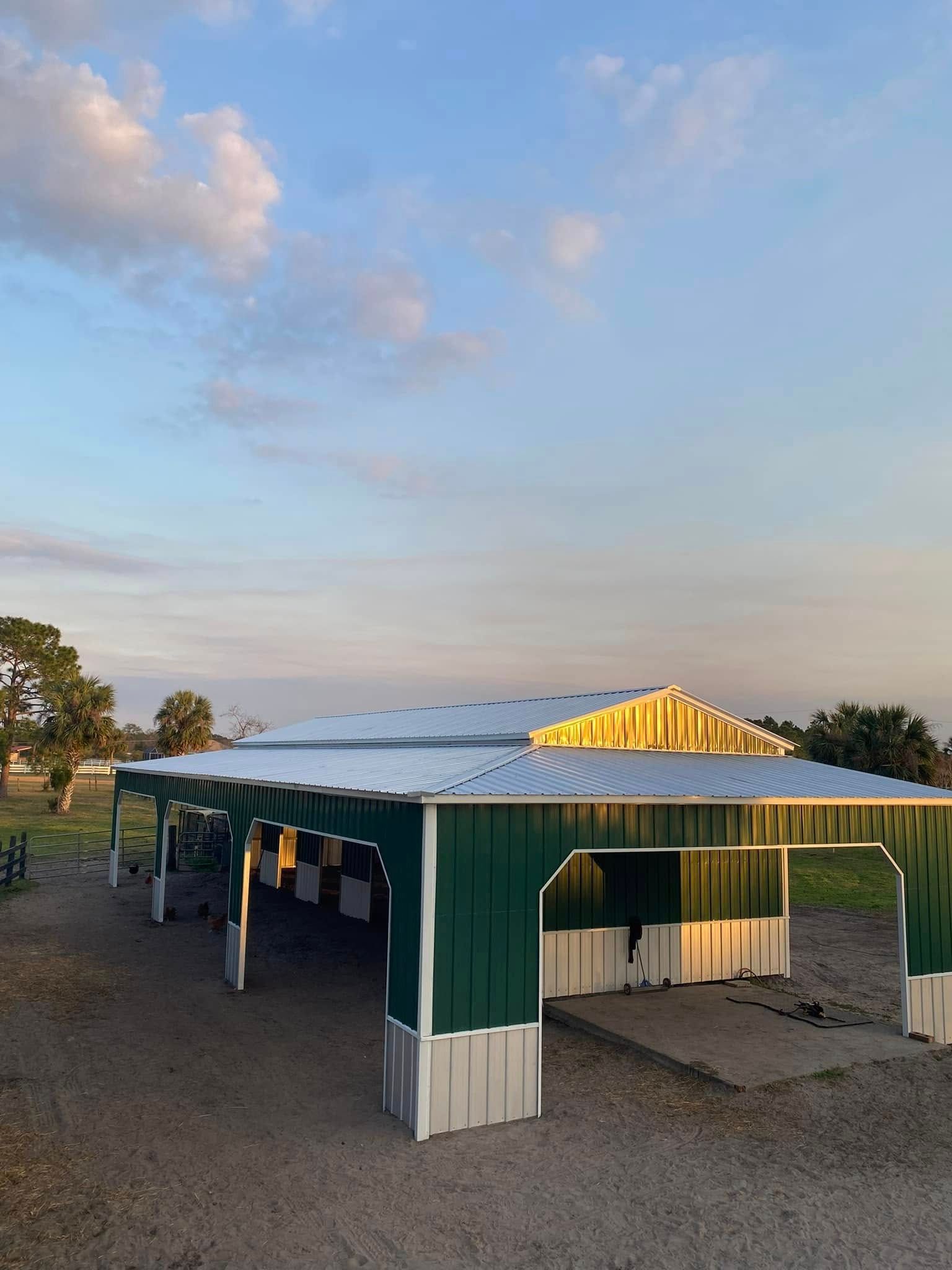 Green and white barn under a blue and pink sky.