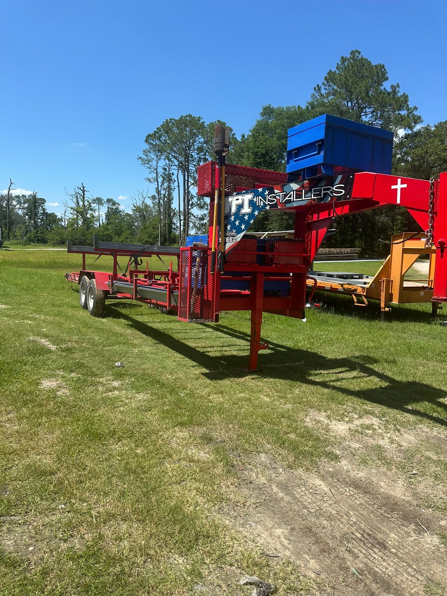 Red and blue trailer with patriotic design on a grassy field under a blue sky.